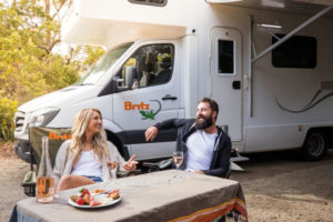 motorhome hire couple sitting relaxing drinking and eating wine strawberries