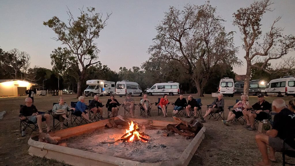 Escorted motorhome tour group around a campfire with Maui motorhomes at camp