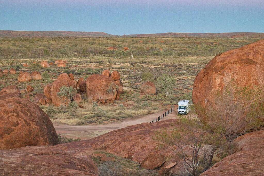 Motorhome on an outback track among red granite boulders in the Australian outback