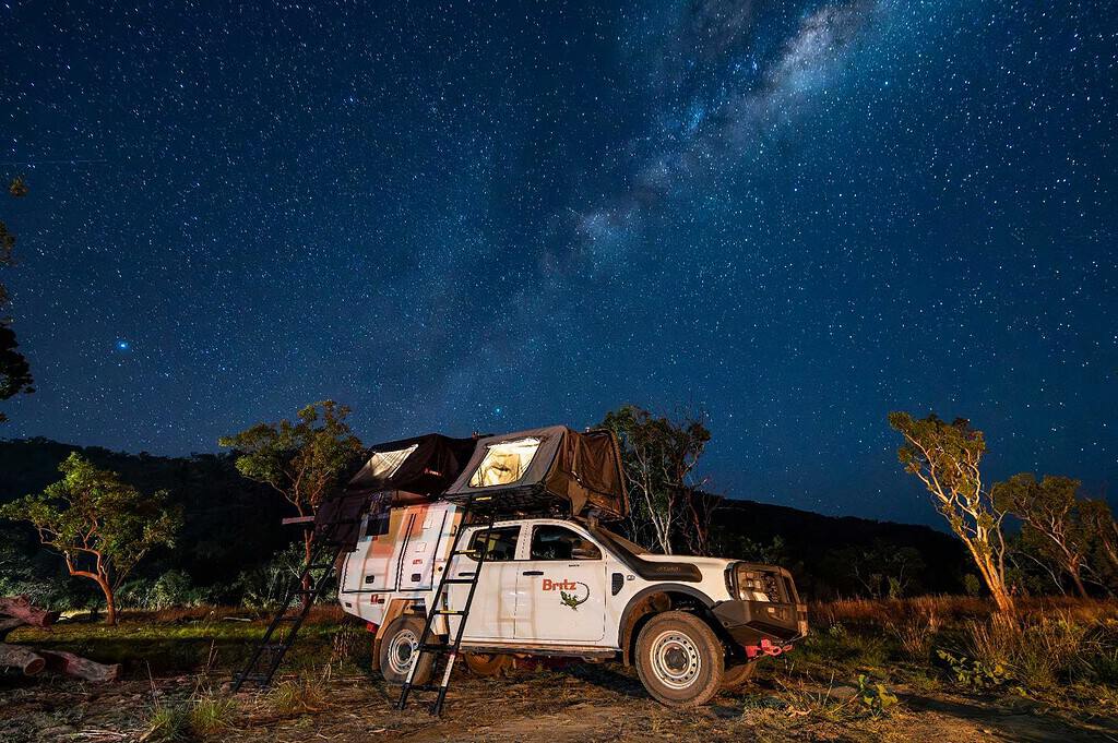 4WD camper with a rooftop tent set up under the Milky Way at a bush campsite