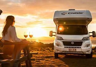 Sunset with a woman enjoying wine on outdoor terrace next to a campervan in Australia.