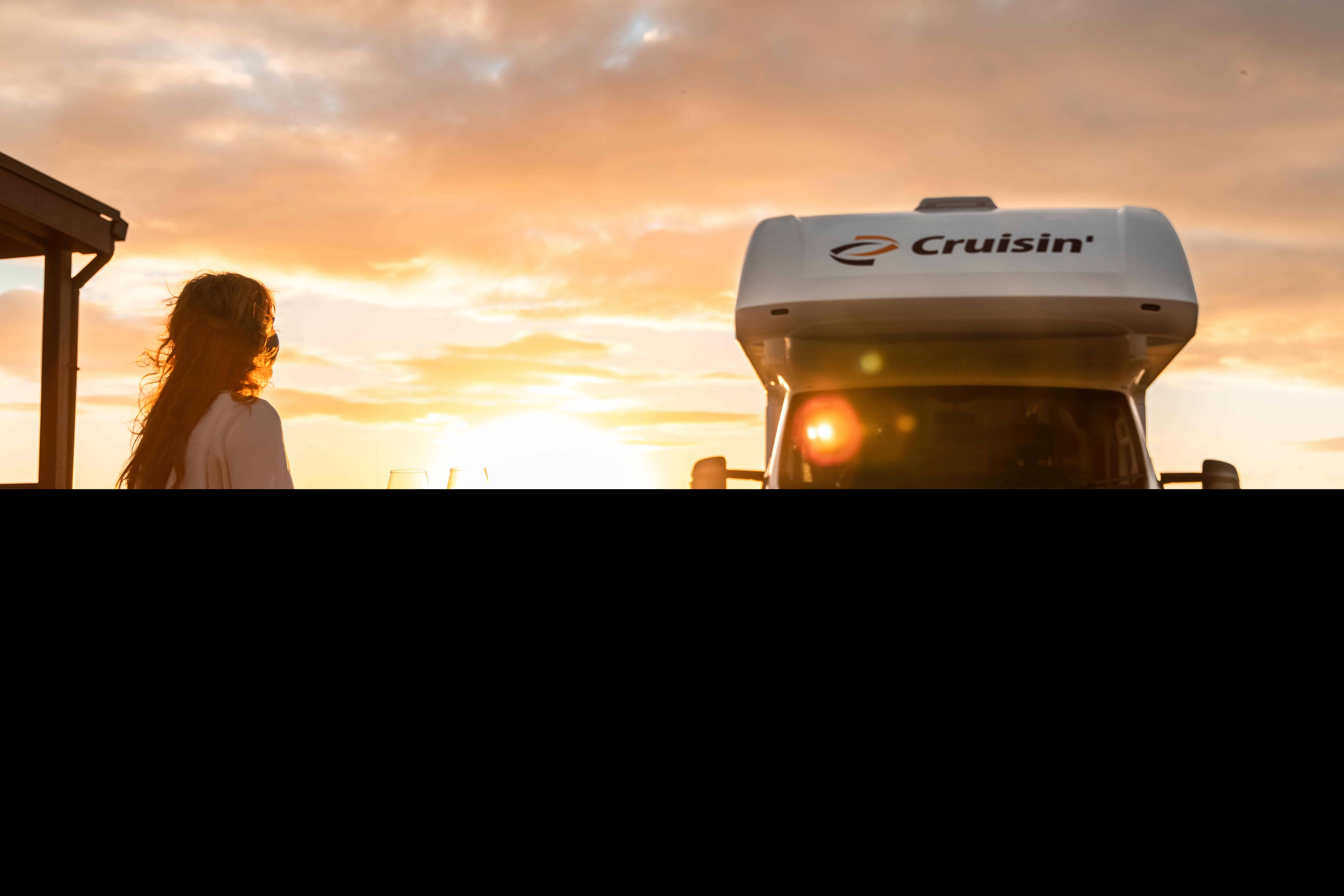 Sunset with a woman enjoying wine on outdoor terrace next to a campervan in Australia.