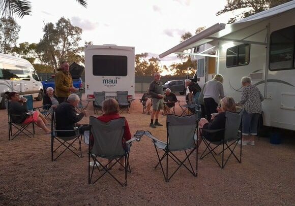 Campers socialising around their Maui campervans against the backdrop of Australian gum trees.