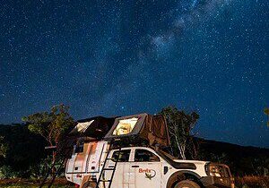 4WD camper with a rooftop tent set up under the Milky Way at a bush campsite