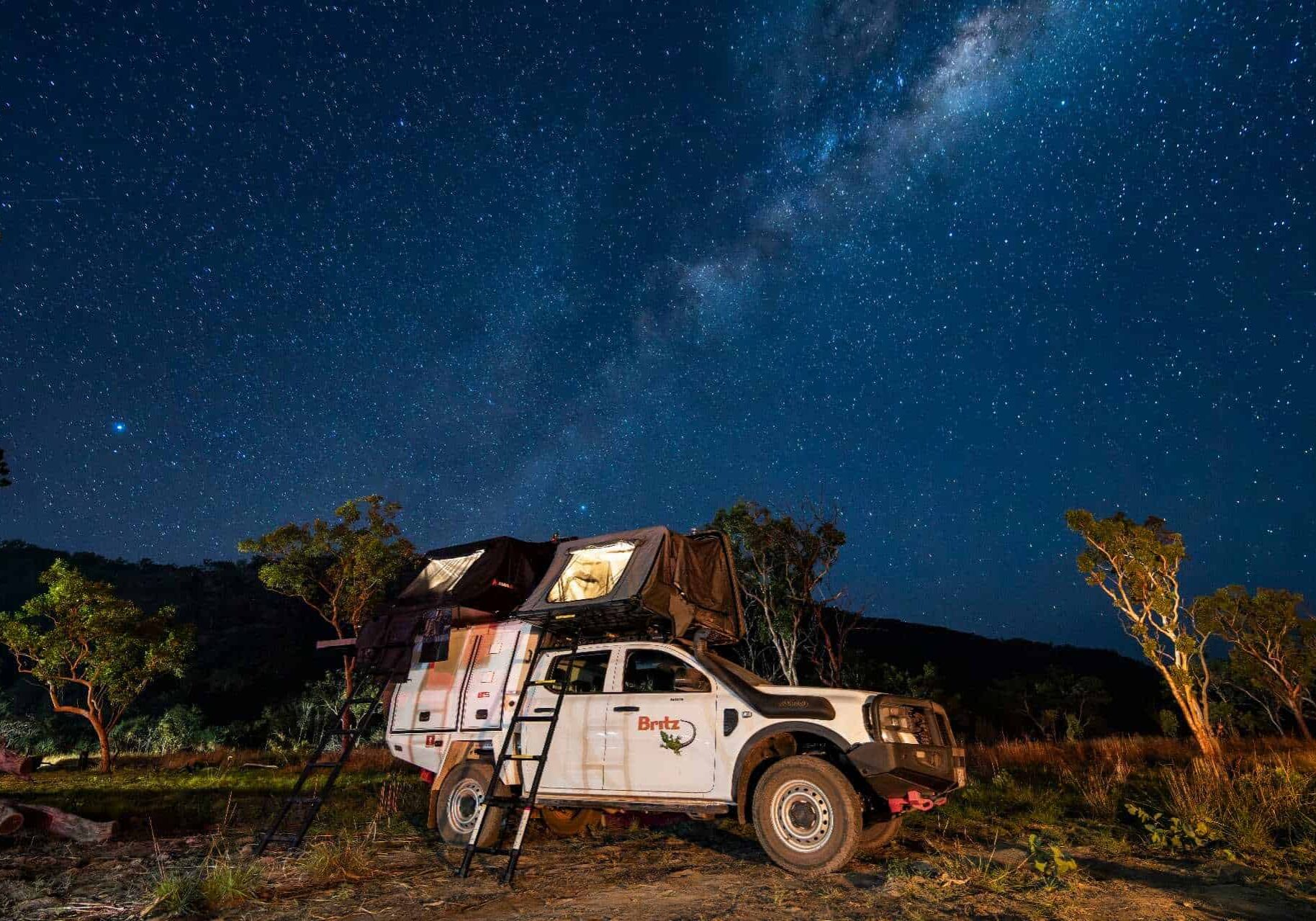 4WD camper with a rooftop tent set up under the Milky Way at a bush campsite