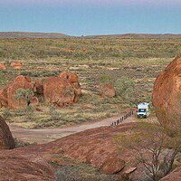 Motorhome on an outback track among red granite boulders in the Australian outback
