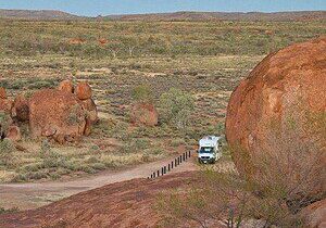 Motorhome on an outback track among red granite boulders in the Australian outback