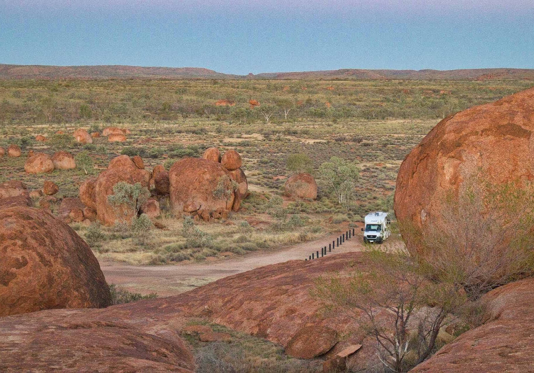Motorhome on an outback track among red granite boulders in the Australian outback